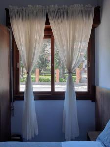 una ventana con cortinas blancas en un dormitorio en Suíte Lago Negro, en Gramado