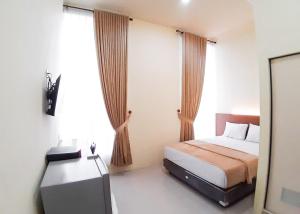 a bedroom with a bed and a television in it at RedDoorz Syariah near Transmart Jambi 2 in Paalmerah