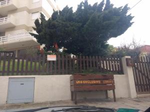 una señal frente a una valla de madera con un árbol en Apartamento Libra 6, en Villa Gesell 1 foto más