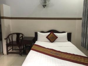 um quarto com uma cama com uma almofada e uma cadeira em Mai Vuong Thuy Hotel em Thu Dau Mot