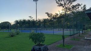 a tennis court with two tennis courts with palm trees at Loft Melhor do Sahy - Magaratiba RJ in Mangaratiba