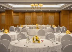 un salón de banquetes con mesas blancas y sillas blancas en Sarovar Portico Surajkund en Nueva Delhi