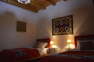 a bedroom with two beds and a tapestry on the wall at Guest House Marokand in Samarkand