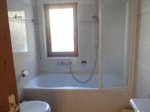 baño con bañera, aseo y ventana en Villa Bernhard, en Siusi