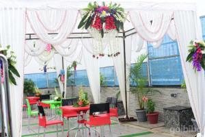 a patio with red tables and chairs under a white canopy at Hotel Madhuvan by TravelkartOnline in Dhanbād