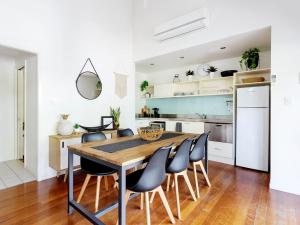 una cucina e una sala da pranzo con tavolo e sedie in legno di Mobys 29 a Boomerang Beach