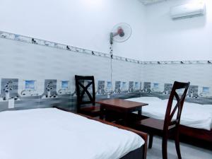 Thu Dau MotにあるNhà nghỉ Đế Vươngのベッド2台、テーブル、椅子が備わる客室です。