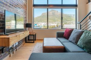 sala de estar con sofá y TV de pantalla plana en Penthouse 2 Bedroom - Biscuit Mill- Apartment, en Ciudad del Cabo