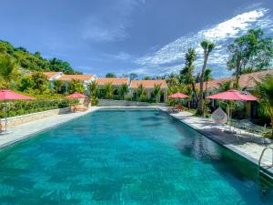 a swimming pool with blue water and red umbrellas at Phu My Hung Bungalow in Phú Quốc