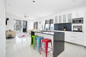 a kitchen with three colorful stools at a counter at Marina Beach Holiday Home in Cremorne