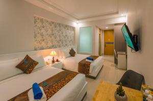 a hotel room with two beds and a television at Nipola Hotel - Chợ Đêm Dương Đông Phú Quốc in Phú Quốc