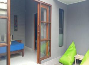 Habitación con puerta de madera y silla verde. en Kawans Inn, en Nusa Lembongan