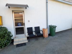two chairs and a trash can next to a building at Apartment Eleco in Bjelovar