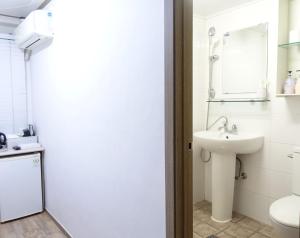 a white bathroom with a sink and a toilet at Gangnam Suncity Guesthouse in Seoul