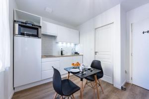cocina con armarios blancos, mesa y sillas en Le Cocon Agenais - Appart'Hôtel SPA - Clim - Melina & Alfred en Agen