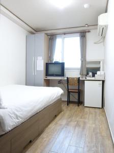 1 dormitorio con 1 cama y escritorio con TV en Gangnam Suncity Guesthouse, en Seúl