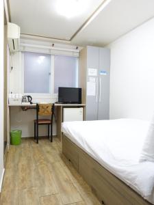a bedroom with a bed and a desk and a kitchen at Gangnam Suncity Guesthouse in Seoul
