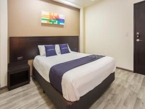 a bedroom with a large bed with blue pillows at Smart Hotel Monterrey in Monterrey
