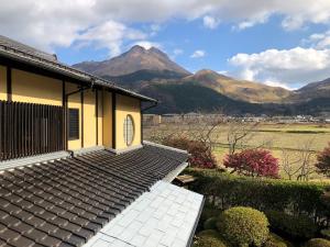 a house with a roof with mountains in the background at Sanso Tanaka in Yufuin