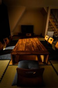 Biker's Inn Onomichi 自転車の宿おのみち في أونوميتشي: غرفة معيشة مع طاولة وكراسي خشبية