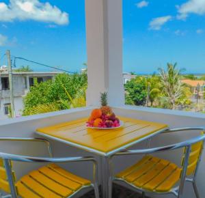 a table with chairs and a bowl of fruit on a balcony at Tulsi Apartment & Studio in La Gaulette