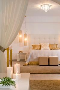 a white bedroom with a bed with two candles at Gold Suites - Small Luxury Hotels of the World in Imerovigli