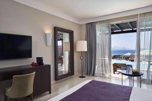 a hotel room with a bed and a large window at Atlantica Belvedere Resort - Adults Only in Kardamaina