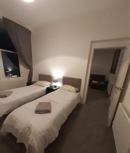 ein Schlafzimmer mit 2 Betten und einem Stuhl darin in der Unterkunft Carvetii - Edward House B - 2 Dbl bed 1st floor flat in Dunfermline