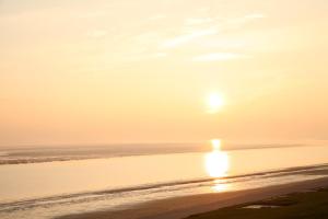 a sunset on a beach with the sun setting at Apart Hotel Seenelke in Wilhelmshaven