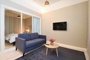 a living room with a blue couch and a bed at Forenom Aparthotel Vaasa in Vaasa