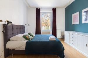 um quarto com uma cama com paredes azuis e uma janela em Travel Homes - The Wooden, Spacieux & bon quartier em Mulhouse