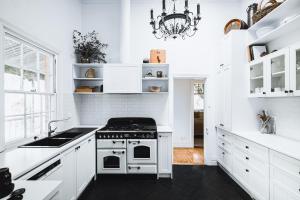 a white kitchen with a stove and a sink at Corvah House in Castlemaine