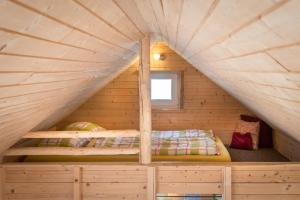 a bed in a wooden cabin with a window at Tiny House Lavender in Podtureň