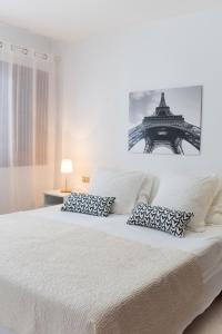 a white bed with two pillows and the eiffel tower at Don Antonio Cristianos Beach Vivienda vacacional in Los Cristianos