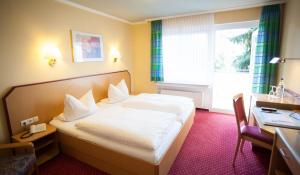 um quarto de hotel com uma cama, uma secretária e uma janela em Hotel Restaurant Zur Post Lohfelden em Kassel