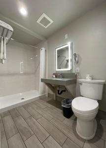 a bathroom with a toilet and a sink and a tub at Budget Lodge Eugene - Airport in Eugene +12 photos