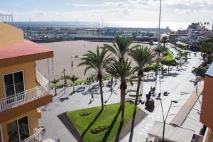 a city street with palm trees and a body of water at Don Antonio Cristianos Beach Vivienda vacacional in Los Cristianos