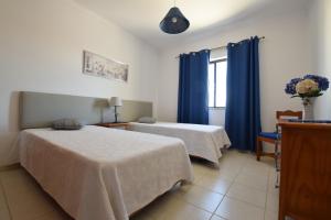 a bedroom with two beds and a window with blue curtains at Apartamentos Carruna in Albufeira +37 photos