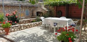 un patio con mesa, sillas y flores en Apartments Roses, en Dobrinj