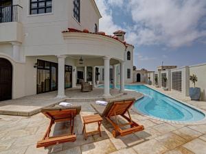 a house with a swimming pool and two chairs at Lagoon Suites Guesthouse CC in Walvis Bay