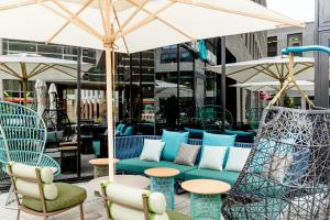 a patio with chairs and tables and an umbrella at Motel One Bonn-Hauptbahnhof in Bonn