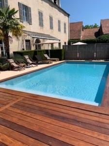 uma piscina com um deque de madeira ao lado de um edifício em Hôtel Le Clos du Colombier 1817 Vignes & Spa em Pommard