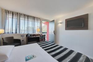 Habitación de hotel con cama y escritorio en Kyriad Bordeaux - Merignac Aéroport en Mérignac