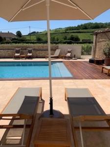 uma piscina com um guarda-sol e duas cadeiras e uma mesa e sidx em Hôtel Le Clos du Colombier 1817 Vignes & Spa em Pommard