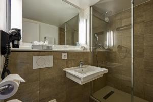a bathroom with a sink and a mirror at Kyriad Bordeaux - Merignac Aéroport in Mérignac +42 photos