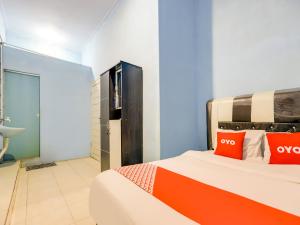 um quarto com uma cama com almofadas laranja em OYO 90009 Faster Inn 1 em Medan