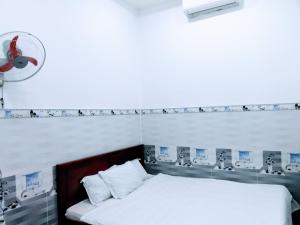 ein Schlafzimmer mit einem Bett und einem Ventilator an der Wand in der Unterkunft Nhà nghỉ Đế Vương in Thu Dau Mot