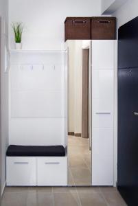 a white cabinet with a bench in a room at Victoria Apartman in Kecskemét +17 photos