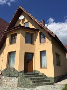 una casa amarilla con una puerta y unas escaleras en Pensiunea Pusu, en Ranca