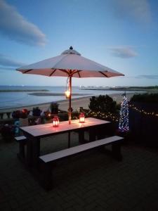 a picnic table with an umbrella and a christmas tree at Captains Lodge in Newbiggin-by-the-Sea